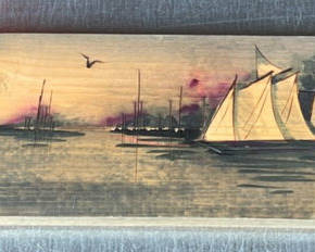Lot 32: Hand-painted wooden panel of a harbor town with sailboats 30" x 6"