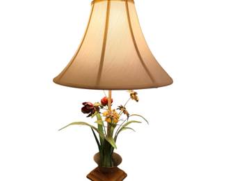 vintage-style table lamp featuring a metal floral bouquet base with painted blooms and green leaves, sitting on a square wooden stand under a flared fabric shade.