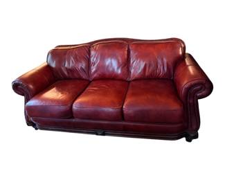 rich burgundy leather sofa accented with classic nailhead trim along the rolled arms and base.