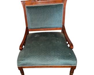 antique wooden armchair upholstered in a teal or green patterned fabric with carved details on the top crest rail and turned front legs.