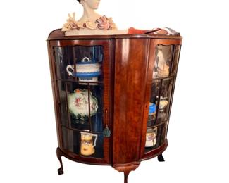 vintage walnut bow-front curio cabinet featuring elegant curved glass doors and classic ball-and-claw feet.