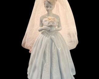 vintage porcelain bride figurine wearing a white wedding gown and a tulle veil, holding a small bouquet.