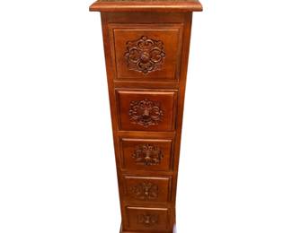 tall, narrow wooden 5-drawer accent chest with carved floral medallion drawer fronts and a warm brown finish.