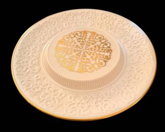vintage Lenox Chalet Cheese Server crafted from cream-colored or ivory porcelain with a raised center platform and intricate embossed scrollwork. It is decorated with a 24-karat gold rim and a matching gold medallion