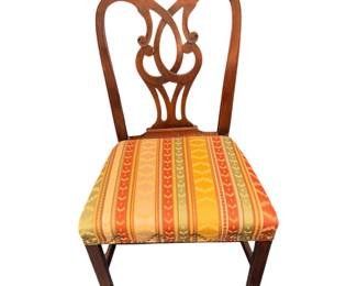 traditional wooden dining side chair featuring an ornate carved shield or ribbon-back design and a vertically striped multicolored upholstered seat with nailhead trim