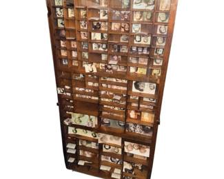 antique wooden printer's tray, also known as a letterpress or type case drawer, featuring multiple small compartments filled with small vintage photos and ephemera.