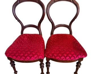 pair of antique Victorian-style balloon back chairs featuring dark wood frames and rich red textured velvet seats.