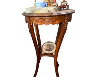 antique wooden accent table with an oval top, carved trim, curved legs, and a lower shelf