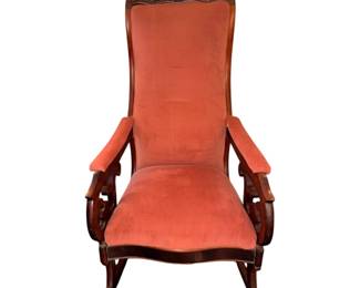 antique Victorian-style rocking chair featuring plush pink upholstery and an ornate carved wooden frame.