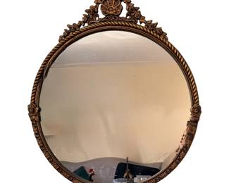 vintage round wall mirror with an ornate gold-tone or gilded frame featuring a rope-twist edge and a decorative floral and shell crest at the top.