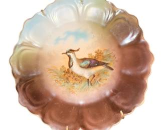 antique porcelain decorative wall plate featuring a hand-painted game bird (such as a lapwing or plover) against a landscape background with a scalloped, iridescent lusterware rim.
