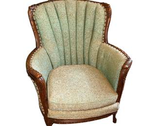 vintage channel-back armchair featuring a fluted, shell-like tufted backrest and ornate carved wood trim with nailhead accents