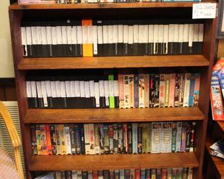 Cd's and VCR Tapes in a wooden book shelf. Book shelf is for sale.