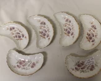 Vintage porcelain crescent-shaped bone dishes with a floral transferware pattern and gold trim.