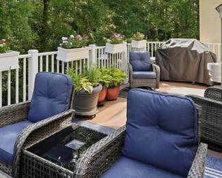 Resin wicker outdoor furniture, pots and planters with live flowers and an outdoor grill