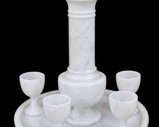 Vintage 1970s White Marble Cordial Decanter & Goblet Barware Set (Made in Taiwan) A stunning, substantial tabletop barware set beautifully hand-carved from solid natural white marble. Featuring subtle grey veining throughout, this minimalist architectural piece includes a majestic tower-shaped liquor decanter with a tiered architectural finial lid. The decanter rests on a perfectly recessed circular matching marble tray accompanied by matching stemmed cordial goblets. A dense, tactile, and highly elegant conversational centerpiece stamped "Made in Taiwan" on the base. "EXCEPTIONAL VINTAGE BARWARE!!"
