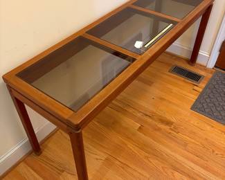 O2 - $250. MCM Danish Teak Console Table with Smokey Glass Panels. Measures 59” W x 19” D x 25.25” Tall. Bottoms of legs show wear.