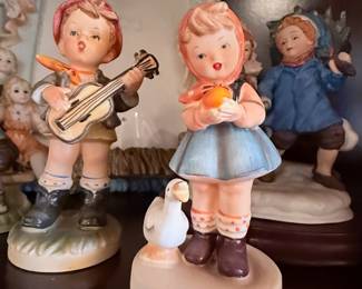 Vintage Hummel-Style Figurine Collection – Charming assortment of porcelain figurines featuring children, angels, musicians, and storybook scenes in hand-painted finishes. A delightful collection for curio cabinets, traditional home décor, or collectors of Hummel-style figurines. Sold individually unless noted.