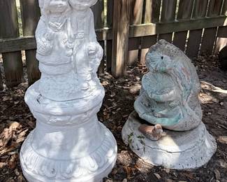 Concrete Garden Statue Collection – Charming assortment of outdoor concrete garden décor featuring a sweet boy and girl on a bench pedestal and a whimsical frog holding lily pads. Perfect for gardens, patios, flower beds, or landscape accents. Sold individually unless noted.