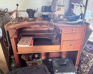 Vintage Jeweler's Workbench – Solid wood jeweler's workbench featuring a curved work surface, bench pin, armrests, multiple drawers, and open storage. Includes an assortment of jewelry-making tools and equipment shown. A fantastic workspace for jewelers, watchmakers, hobbyists, or metalsmiths. Contents sold separately unless noted.