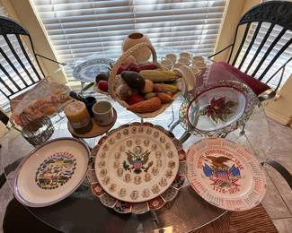 Assorted Decorative Plates & Tabletop Décor – Collection featuring commemorative and patriotic collector plates, decorative floral glassware, artificial fruit displays, candles, mugs, and assorted tabletop accents. A nice mix of vintage home décor, holiday pieces, and display items. Sold individually unless noted.