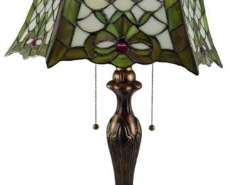 183 - Tiffany Style Stained Glass Table Lamp 24" (Description): Tiffany style stained glass table lamp featuring a decorative shade with green, white, and cream colored glass panels arranged in a floral and geometric pattern with red glass jewel accents. The scalloped shade sits atop a bronzed metal base with Art Nouveau inspired design and dual pull chain switches. The baluster-form base features fluted details and a circular footed bottom. Electric/electronic/mechanical item - No
