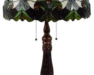 193 - Tiffany Style Stained Glass Table Lamp 29" (Description): Tiffany style stained glass table lamp measuring 29 inches tall. The dome shade features an Art Nouveau-inspired design with cream and white panels accented by green leaf motifs, amber jewel accents, and dark leading in a scalloped edge pattern. Thelamp rests on a cast metal base with a bronzed finish and ornate scrollwork detailing on decorative feet. Equipped with dual pull chain switches.