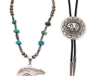 1330 Two Southwest sterling silver bear-motif jewelry items Two works:  Emerson Kinzel (20th century, Diné [Navajo]) A round sterling silver overlay concho-style bolo with a heartline bear motif and hooked border, with stampwork edging, set to a black braided leather cord with silver cone-and-ball tips Stamped: EK [conjoined] / Sterling Bolo diameter 2 1/2 in.; cord 44 in.  A sterling silver heartline bear pendant suspended on a single strand of silver beads with turquoise nuggets Pendant bail stamped: Sterling / [sunrise sunburst] 18 1/2 x 2 3/4 in.  2 pieces total 107.4 grams gross Estimate: $200 - $300