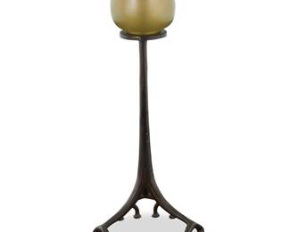 1245 A Tiffany Studios bronze 'Root' candlestick Early 20th century with later married elements The root-form base with altered support raising an associated iridescent pulled feather glass shade Impressed: TIFFANY STUDIOS / NEW YORK / 1200 Height overall 13 3/8 in., diameter 5 1/2 in. Estimate: $700 - $1,000