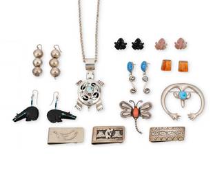 1409 A group of Southwest silver jewelry Mid/late 20th century Twelve works comprising a sterling silver turtle pendant/brooch with set turquoise on a silver chain, a silver naja pendant/brooch with set turquoise, and a repoussé dragonfly brooch with set orange stone, as well as six pairs of earrings in various styles including a pair of set spiney oyster earrings by Esther Wood (b. 1946, Diné [Navajo]) as well as carved stone and jet fetish frogs and jet heartline bears, silver beads, and set blue stones with silver dangles, and three money clips in various designs including a Kokopelli overlay motif Variously stamped for artist: Esther [etched script] / R / S [within a V] / WW / RB / D; four stamped for Sterling 18 pieces Necklace 21 x 3 in.; pendant/brooch 2 1/8 x 2 3/8 in.; clips 1 x 2 in.; earrings 2 1/4 in. to 5/8 in. 189.6 grams gross Estimate: $200 - $400