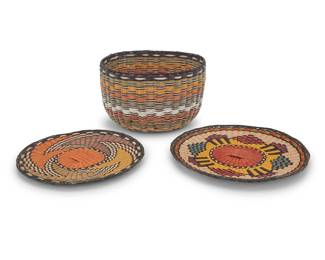 1177 Three Hopi polychrome wicker basketry items Mid/late 20th century; Arizona Comprising a large twined wicker basket, as well as two polychrome twined wicker plaques, each with geometric motifs 3 pieces Basket height 8 in., 13 1/3 in. approximately; plaques each height 1 in.; diameters 14 1/2 in. and 13 in. Estimate: $200 - $400