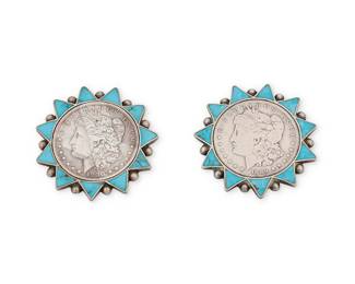 1373 A pair of Zuni silver coin and turquoise pins Mid-20th century Each designed with a Morgan silver dollar framed within a turquoise-inlaid sunburst surround with silver drop accents. Unmarked Each diameter 2 1/8 in. 97.3 grams gross Estimate: $800 - $1,200