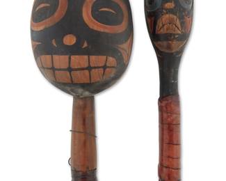 1143 Two Northwest Coast polychrome-painted cedar rattles Second half 20th century Comprising a large oval two-sided rattle with painted stylized facial motifs and a small two-sided rattle with painted carved facial motifs, each with a leather-wrapped handle 2 pieces Larger height 9 in., width 3 3/4 in., depth 3 1/4 in.; smaller height 8 3/4 in., diameter 1 7/8 in. Estimate: $200 - $400