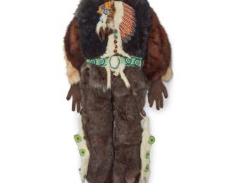 1130 A large contemporary Cree beaded pictorial doll sculpture with fur Attributed to Jack Little Boy (20th/21st century, Canadian Cree) Entitled "Chief Carrier," circa 1988 The tall doll-like articulated soft figure with beaded portrait face, dressed in various fur pelts, with ermine and beadwork accents to center front, including a beaded chief portrait plaque with feathered headdress, a beadwork belt, and ermine leg bands, with suede hands and hair-on-hide footwear Unmarked Height 2 ft. 11 in., width 1 ft. 3 in., depth 4 1/2 in. approximately Estimate: $300 - $500