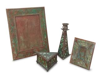 1368 Four Riviere Studios bronze and glass desk items Early 20th century Verdigris patinated, comprising two easel-back pine frames with pine needle design and a triangular box with holly design, together with a slag glass and grape leaf filigree candlestick Candlestick marked: TIFFANY STUDIOS NEW YORK; largest frame personalized with initials 'H E' 4 pieces Larger frame aperture 9 3/4 x 7 3/4 in.; smaller aperture 3 3/8 x 2 1/4 in.; height of candlestick 10 in.; height of box 3 3/8 in., width 6 1/8 in., depth 5 1/4 in. Estimate: $700 - $900