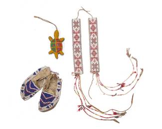 1120 A group of Plains beaded items 20th century Three works comprising a Lakota (Sioux) polychrome beaded hide umbilical cord fetish turtle figure, a pair of polychrome on white beaded arm bands with quill tassels and metal cone dangles, and a pair of child's beaded moccasins in blue, red, and white stepped and geometric motifs 5 pieces Turtle height 5 1/2 in., width 3 in., depth 1 1/4 in.; strap 5 5/8 in.; moccasins height 7 1/2 in., width 3 1/2 in., depth 1 in. approximately; armbands 1 3/4 in. x 10 3/4 in.; tassels 16-15 in. approximately Estimate: $400 - $600