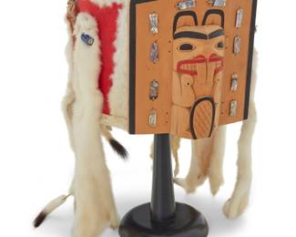 1150 Mike Epp (b. 1962, Gitlaan/Coast Tsimshian) A Northwest Coast headdress with central polychrome carved wood frontlet featuring a standing beaver figure and abalone and bird quill accents, the frontlet attached to the red felt tradecloth-covered framework, all trimmed with ermine fur, mother-of-pearl discs, and six ermine pelts topped with blue and red striped trade beads, all sinew-stitched and mounted to a birch-strip framework Frontlet inscribed verso: ME [conjoined, partially visible behind framework]; partial view of inscription below: Coast Tsimshian, Gitlaan Tribe, Raven Clan, Metlakatla, B. C. Height 6 1/2 in., width 8 in., depth 9 in.; pelts hang approximately 9 in. below edge Estimate: $600 - $800