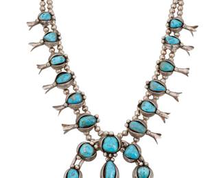 1391 A Southwest sterling silver and turquoise squash blossom necklace Mid-20th century A chunky double strand necklace with twelve ornate graduated set turquoise blossoms with applied feather motifs, all suspending a large two-wire set turquoise naja with central stone and silver ball accents Unmarked 29 x 4 1/4 in. 325.4 grams gross Estimate: $600 - $800