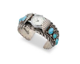 1354 Orville Tsinnie (1943-2017, Diné [Navajo]) A chunky sterling silver watch cuff with five graduated set turquoise cabochons to each shoulder and heavy stamping to edges, with attached watch face Stamped: TSINNIE / Shiprock / NM / [Shiprock motif] / Sterling 6 in. total inner C x 1 in., including a 1 in. gap 66.4 grams gross Estimate: $400 - $600