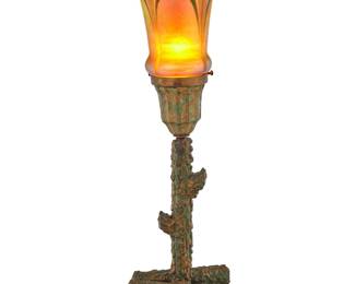 1262 A Miller Lamp Co. table lamp and pulled feather glass shade 20th century The patinated and gold-toned metal base with single light and a pulled feather iridescent glass shade, electrified Shade later etched: V652893; base unmarked Height of base 11 3/8 in., width 5 1/2 in., depth 5 in.; height of shade 6 in, diameter 5 5/8 in; overall height 17 1/4 in. Estimate: $300 - $500