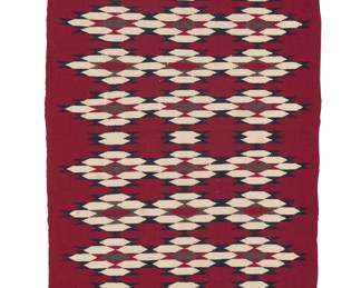 1276 A Diné (Navajo) regional rug Second half 20th century A long textile woven in red, cream, black, and dark brown wool with multiple bands of conjoined diamonds 4 ft. 10 in. x 2 ft. 4 1/2 in. approximately Estimate: $500 - $700
