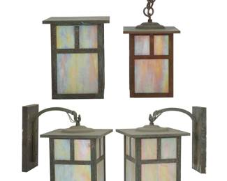 1313 Four Arroyo Craftsman Arts & Crafts-style lanterns Early 21st century The patinated brass cases with iridescent slag glass panels housing a single light, comprising one pair of lanterns hanging from arms issued from wall-mounted escutcheons, one lantern mounted flush with wall, and another ceiling-mounted, electrified Each with factory label applied to escutcheon interior 4 pieces Height of pair lantern only 11 in., width 7 1/4 in., depth 7 1/4 in; height of flush 8 3/4 in., width 7 1/4 in., depth 7 1/4 in.; overall height of ceiling 15 1/2 in., width 6 1/8 in., depth 6 1/8 in. Estimate: $300 - $500