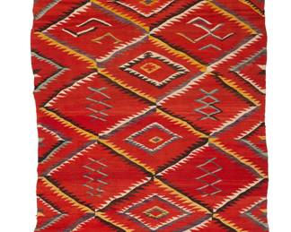 1209 A Diné (Navajo) transitional weaving Circa 1880-1900 Woven in red and multicolored wools featuring a serrated diamond lattice enclosing floating zigzag and two-tone elements, with banded ends 7 ft. 4 in. x 4 ft. 7 in. approximately Estimate: $1,200 - $1,800