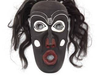 1146 A Northwest Coast polychrome carved cedar 'Dzunuk'wa' mask Second half 20th century A likely Kwakwaka'wakw (Kwakiutl) Tsonoqua mask in black, red, and white pigment, with black hair, likely depicting Dzunuk'wa, or the 'Wild Woman of the Woods' Marked in ink verso: NW 61 Height 13 1/8 in., width 7 1/4 in., depth 3 5/8 in. Estimate: $200 - $400
