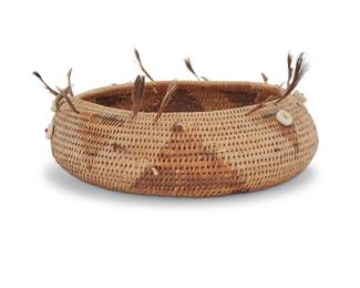 1163 A Pomo beaded gift basket Early/mid-20th century; Northern California A diminutive coiled basketry bowl with alternating triangle motifs, adorned with shell disc button beads and quail topknot feathers Height 1 1/2 in., diameter 4 3/4 in. (variable) Estimate: $300 - $500