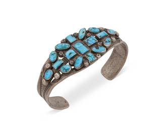 1369 A Diné (Navajo) or Zuni sterling silver and turquoise cuff bracelet Mid-20th century A three-wire pierced cuff with cluster-set oval and rectangular turquoise, stamped silver button accents and stampwork to shoulders 6 1/2 in. total inner C x 1 in., including a 1 1/4 in. gap 38.7 grams gross Estimate: $1,000 - $1,500