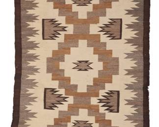 1270 A Diné (Navajo) regional rug Mid-20th century Woven in cream, dark brown, mottled brown, and tan wool with a column of central conjoined stepped diamonds, with floating sawtooth motifs and a complex sawtooth border to the long edges 6 ft. 4 in. x 3 ft. 4 in. approximately Estimate: $600 - $800