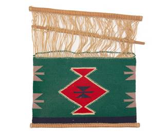1218 A Diné (Navajo) Germantown loomer Early 20th century Woven in green, red, blue, cream, and grey wool, with a central serrated diamond motif and triangular motifs to sides, with cotton warps and wooden loom bars and rods 1 ft. 4 in. x 1 ft. 4 in. Estimate: $300 - $500