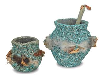 1419 Two Zuni Pueblo turquoise encrusted pottery fetish jars Second half 20th century Each jar with applied ground turquoise chips and mounted with carved stone fetish animals and feathers, the larger jar with a turquoise encrusted figural carved wood stick inserted into a hole in the side, and with multiple corn kernels placed inside the jar 3 pieces Larger height 3 3/4 in., diameter 4 in.; smaller height 2 1/2 in., diameter 2 3/4 in.; stick height 5 1/8 in., height 3/8 in. Estimate: $200 - $400