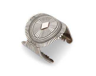 1379 Ron Bedonie (b. 1967, Diné [Navajo]) A sterling silver concho-style cuff bracelet with extensive incised fine line details Stamped for artist and for sterling 7 3/8 in. total inner C x 2 5/8 in., including a 1 5/8 in. gap 140.3 grams Estimate: $400 - $600